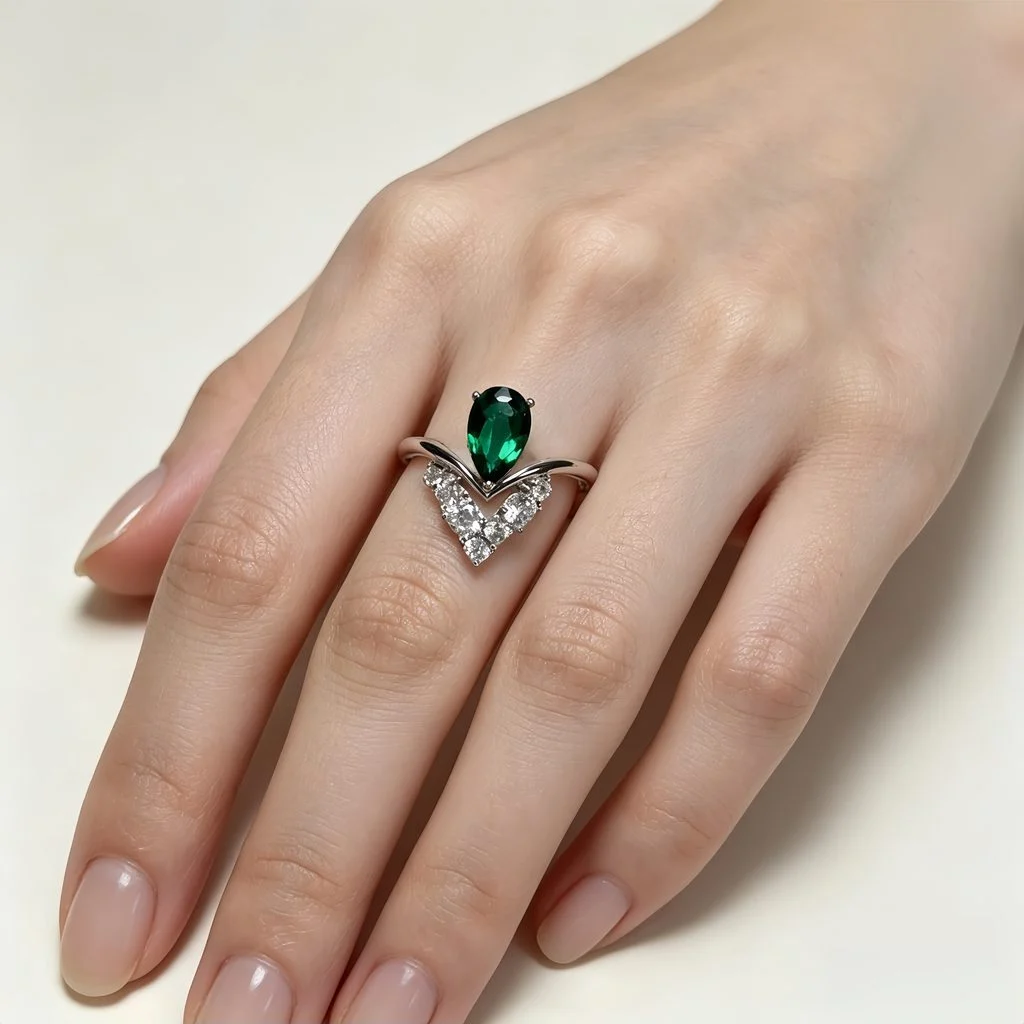 Hand wearing lab-grown emerald crown ring with pear-cut emerald and V-shaped lab diamonds in S925 sterling silver, white background