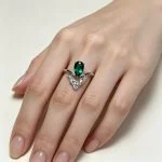 Model wearing lab-grown emerald crown ring on hand, showing actual size and V-shaped diamond setting in S925 sterling silver, white background