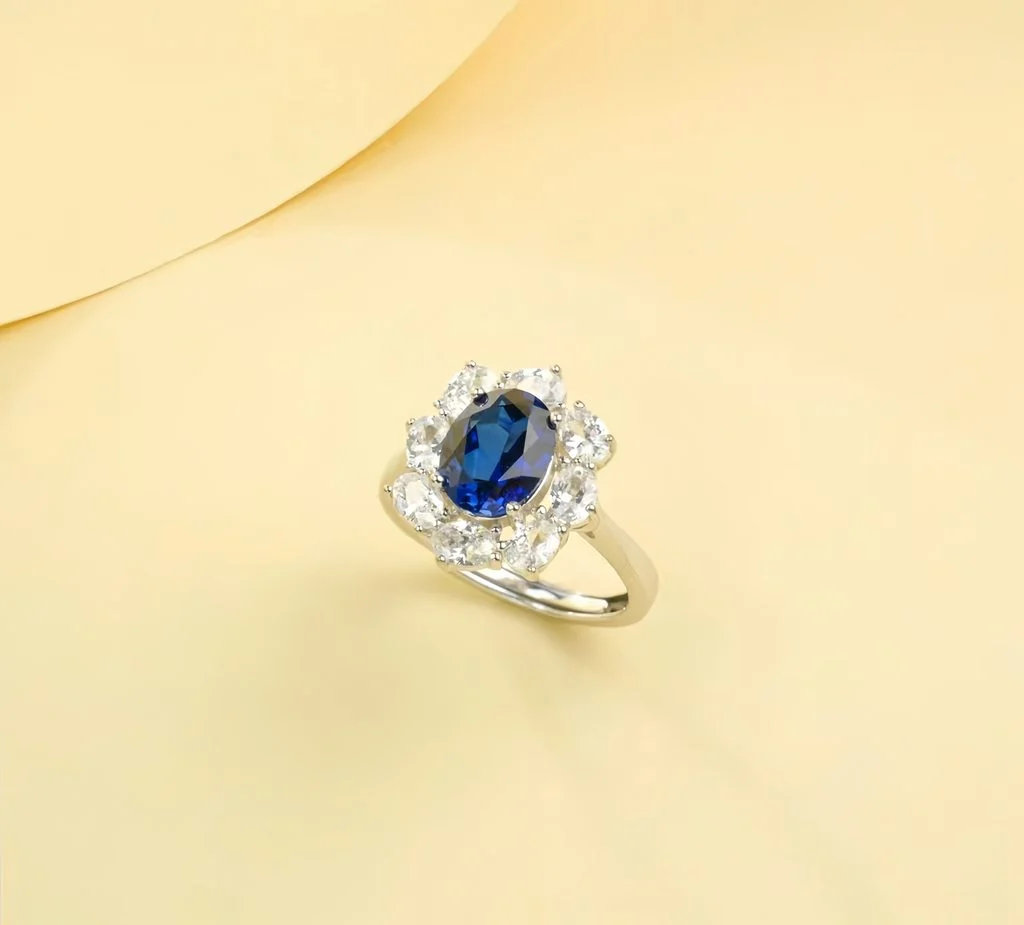 Side profile view of lab-grown blue sapphire sunflower halo engagement ring, showing band thickness and S925 hallmark stamped on inside of band, displayed on warm yellow background