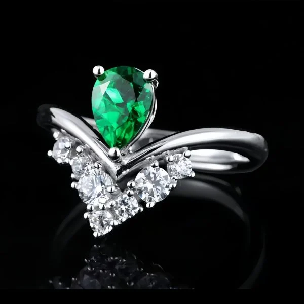 Pear-cut lab-grown emerald ring in V-shaped crown setting with lab-created diamonds and twisted sterling silver band, side angle view on black reflective background