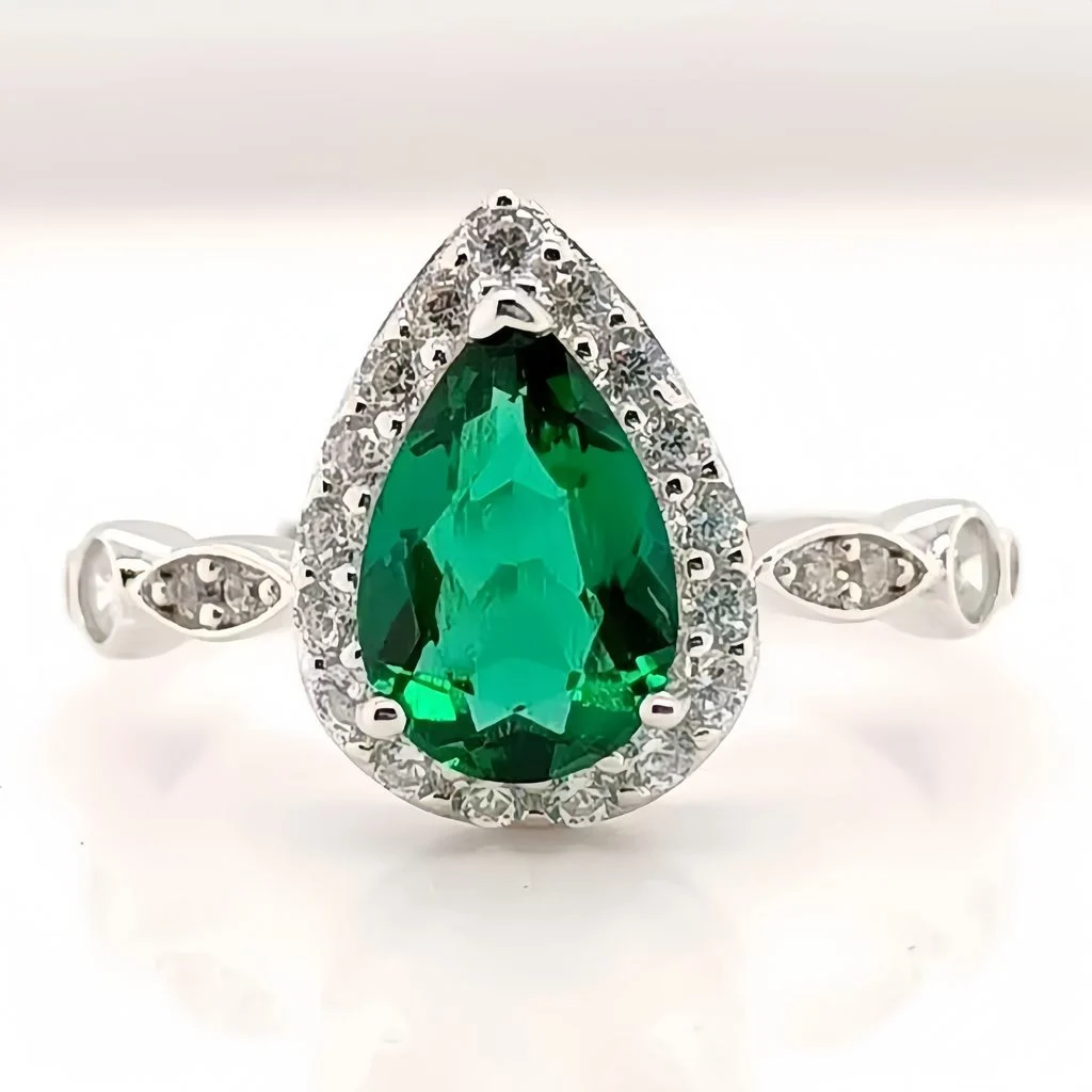 close up detail of lab grown emerald green pear diamond halo ring S925 sterling silver milgrain detail