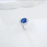 close up detail of lab grown flat oval halo blue diamond ring S925 sterling silver accent stones