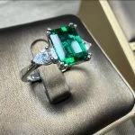 lab grown emerald three stone ring S925 sterling silver top-down flat lay view emerald cut green gemstone pear shaped diamond accents adjustable open band