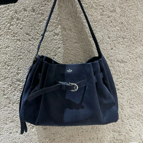 Navy genuine leather buckle hobo shoulder tote bag, front view against textured wall