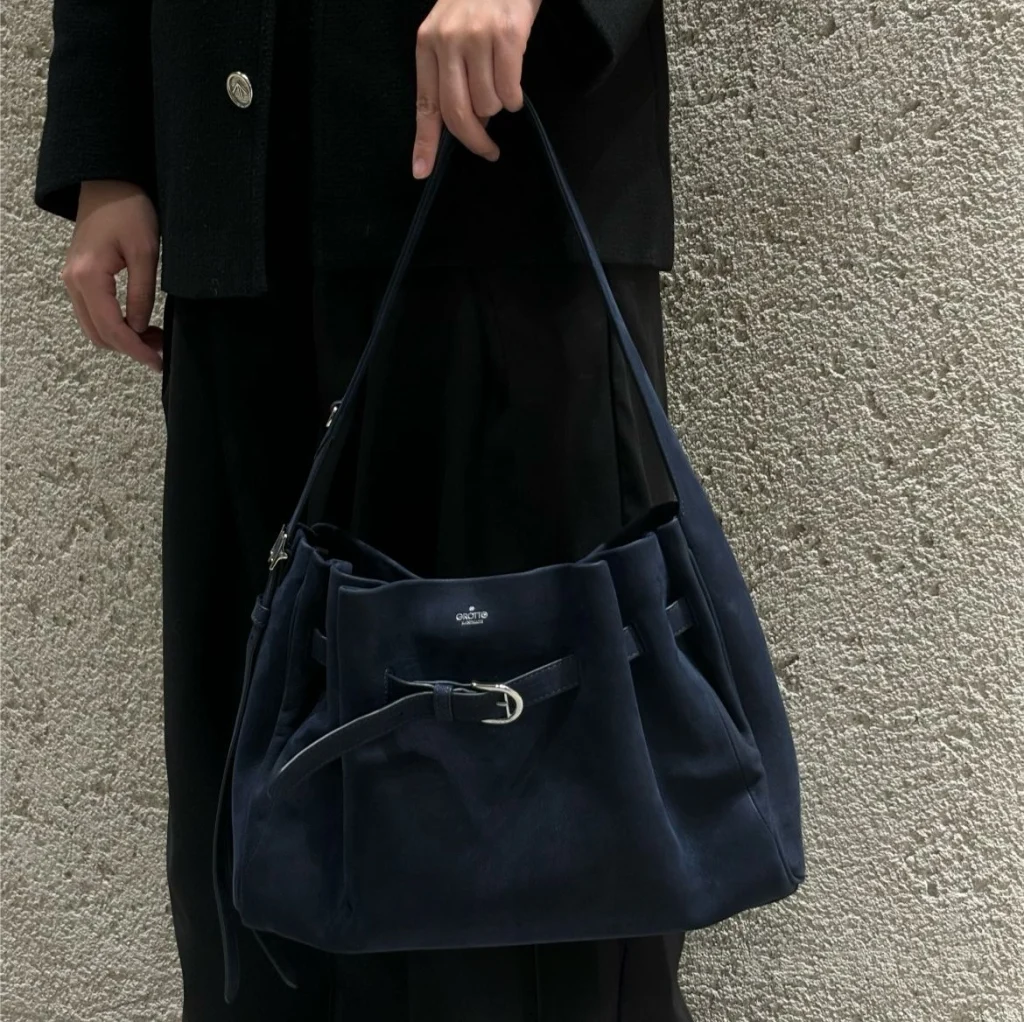 Model carrying navy genuine leather buckle hobo tote bag, everyday commute outfit look
