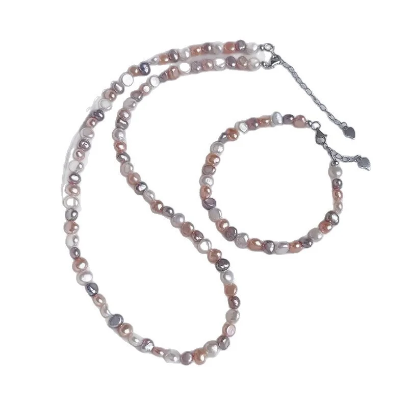 Natural freshwater baroque pearl necklace laid flat on light surface, showing multicolor pearls in white, peach, lavender, and rose gold tones with silver-toned lobster clasp and heart-shaped extender charm by MAISON ELARA & CO