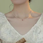 Model wearing dainty pearl choker necklace with burgundy crystal, French style jewelry on neck