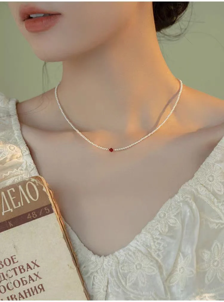 Close-up of faceted wine-red zirconia centerpiece on 2mm Swarovski pearl choker necklace, detailed jewelry shot