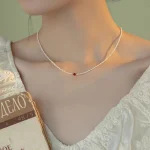 Close-up of pearl choker necklace with burgundy crystal accent, detailed jewelry photography