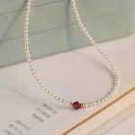 Dainty pearl choker necklace styled in jewelry box with book, elegant flat lay photography