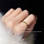 Vintage gold ring worn on finger with feather decor, elegant dark background jewelry photography