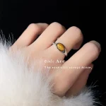 Vintage gold ring with dark oval gemstone worn on finger, white fur decor, atmospheric jewelry photography