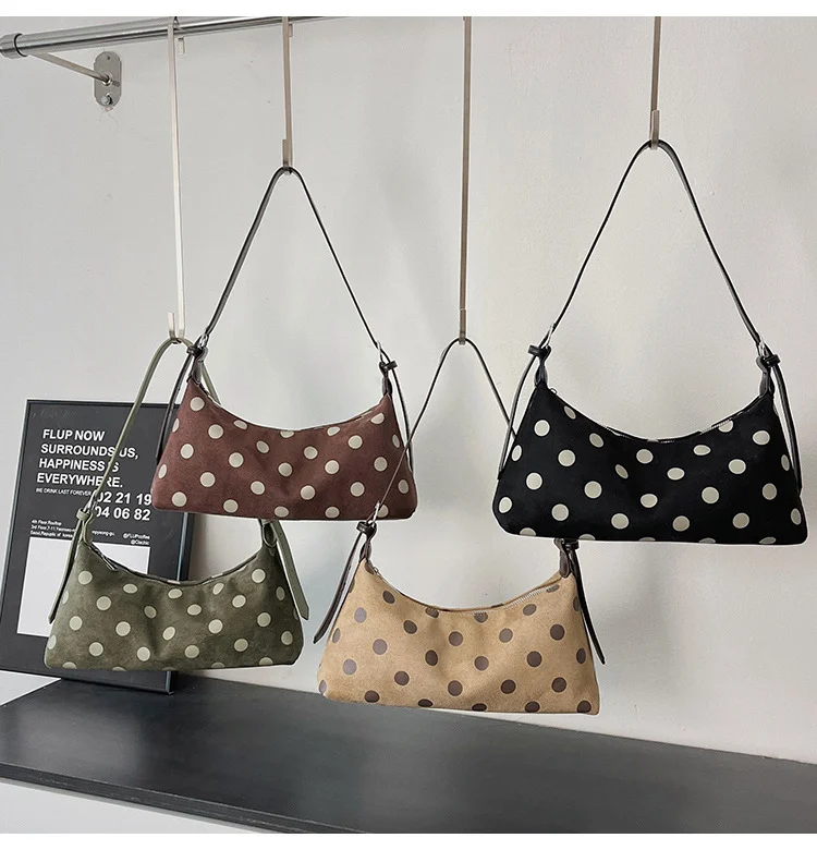 Beige polka dot suede hobo bag styled on bed with book and glasses, lifestyle scene photography