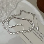 S925 sterling silver brushed bean necklace flat lay on light background with brand card, minimalist jewelry