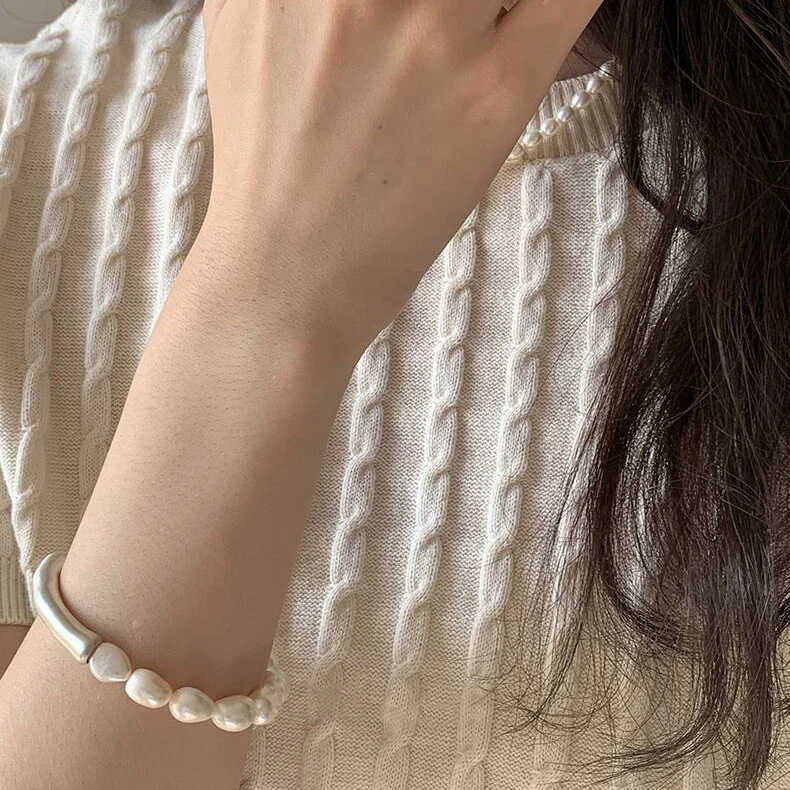 Baroque pearl bracelet on arm wearing cream cable-knit sweater showcasing organic irregular pearl shapes and natural wabi-sabi aesthetic for everyday wear