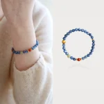 Model wearing a handmade blue crystal and South Red agate beaded bracelet on her wrist, with a matching bracelet laid flat beside it