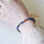 Blue crystal and South Red agate beaded bracelet worn on a wrist, close-up against a soft light background