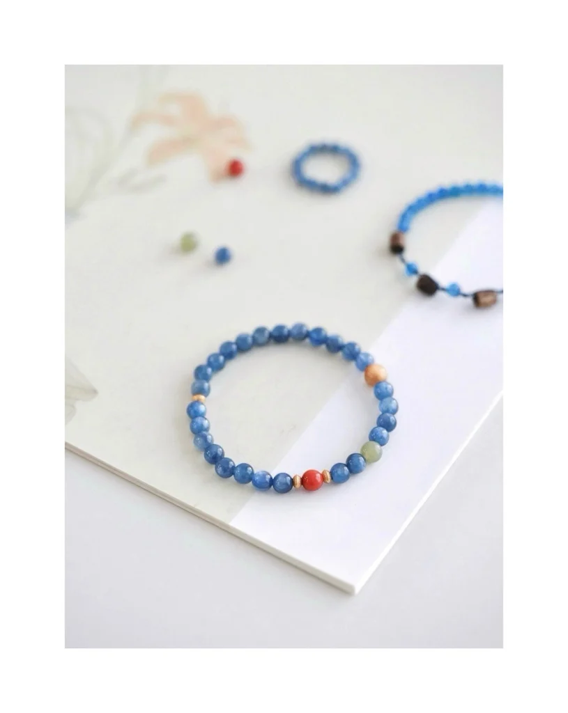 Handmade blue crystal and South Red agate beaded bracelet worn on a wrist beside the same bracelet laid flat
