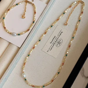 Natural stone and baroque shell beaded necklace laid flat, showing the gold-tone chain, clasp and extender