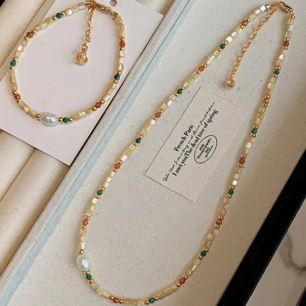 Natural stone and baroque shell beaded necklace laid flat, showing the gold-tone chain, clasp and extender