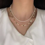 Model wearing the natural stone and baroque shell beaded necklace over a white top