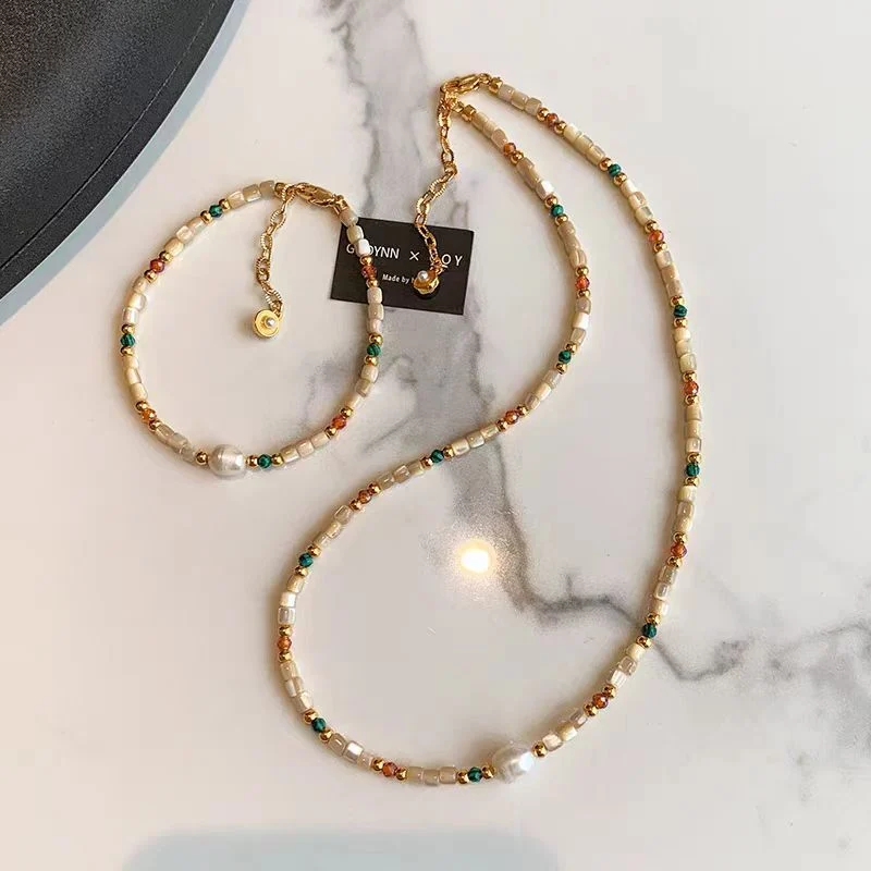 Two necklaces layered on a model, with the natural stone and shell beaded strand over a finer chain