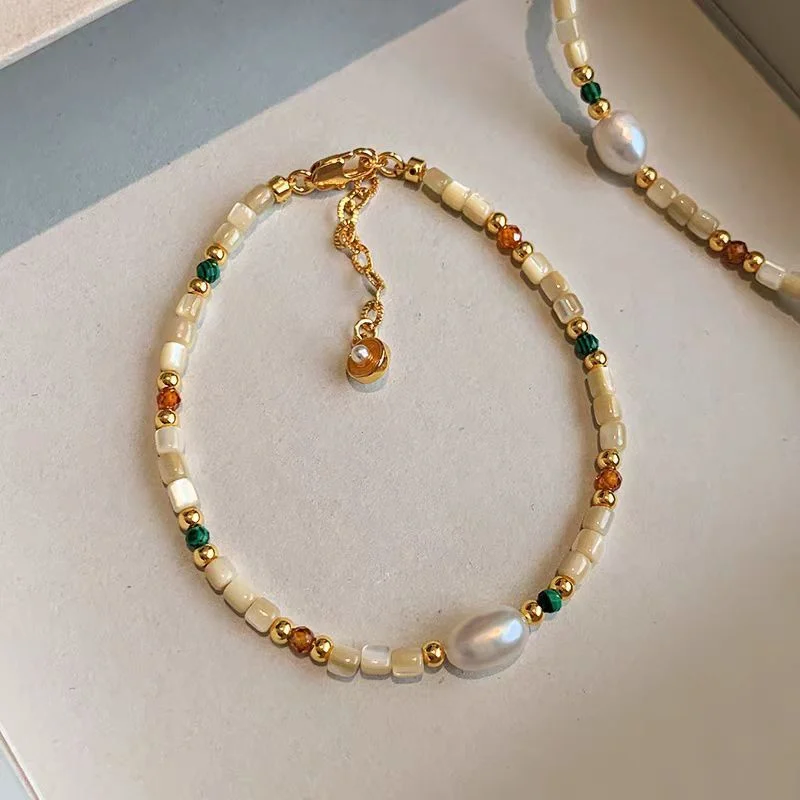 Natural stone and shell beaded necklace worn as a single long strand, showing the drop length