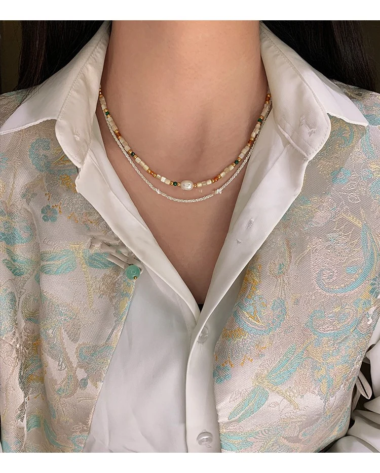 Model wearing the natural stone and shell beaded necklace over a white top
