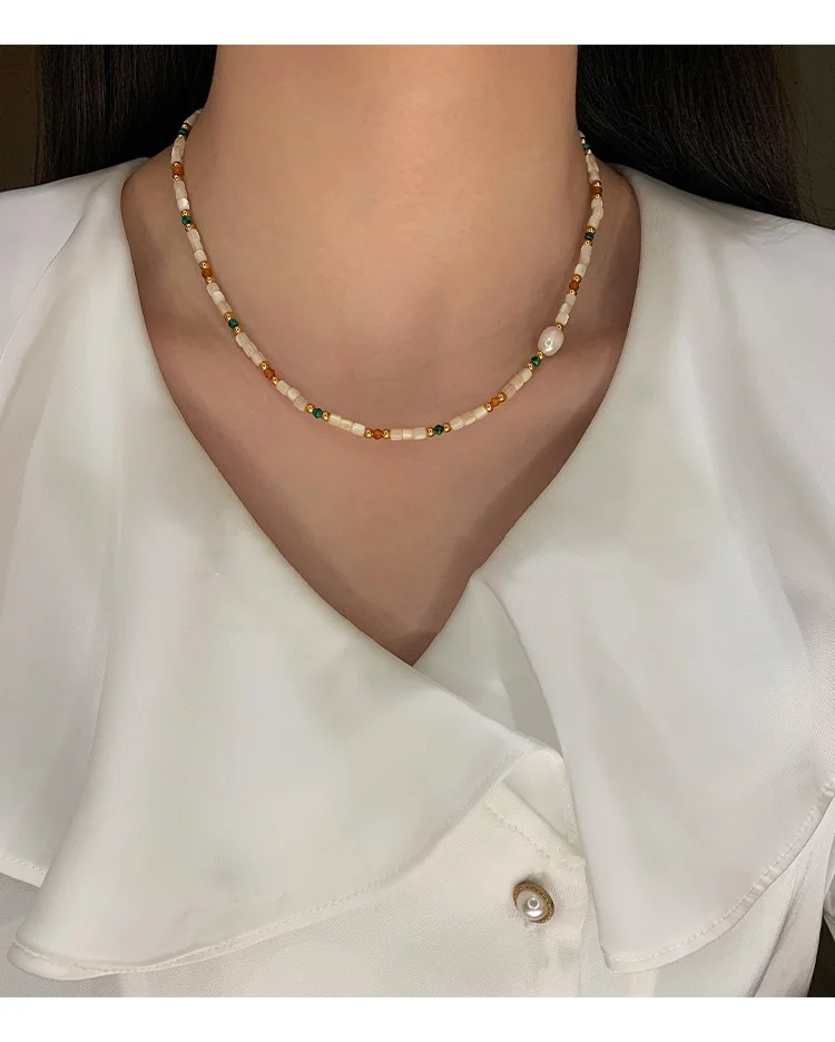 Model wearing the natural stone and shell beaded necklace over a white shirt