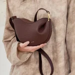 Dark brown genuine leather pea hobo bag, model holding luxury women crossbody purse