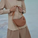 Model wearing tan genuine leather pea hobo crossbody bag seaside fashion shot