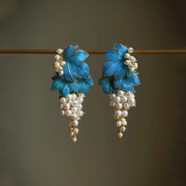 Pair of gold tone blue enamel grape earrings with faux pearl drops, vintage Chinese style, hanging on a display bar