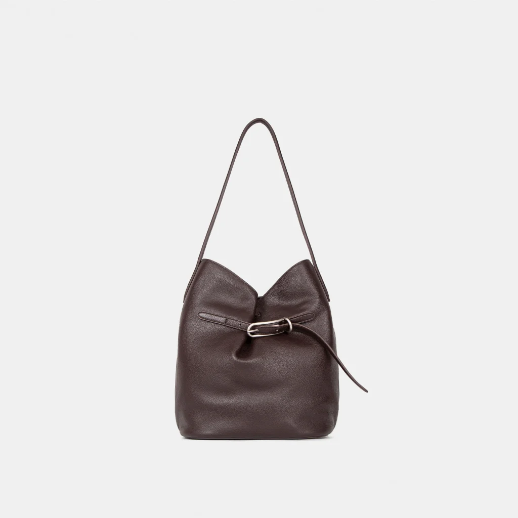 Close-up macro shot of top-grain cowhide leather texture of Lock-Top Bucket Bag, showing natural leather grain