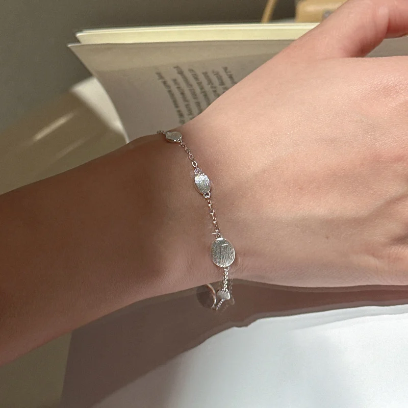 S925 sterling silver bracelet layered with a pearl necklace and light blue outfit