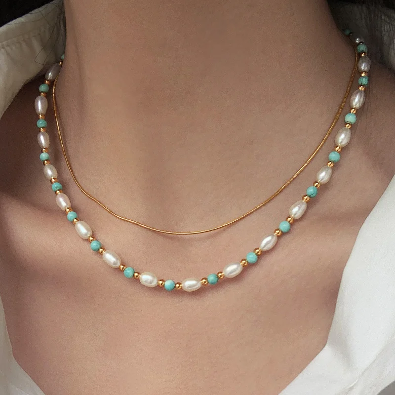 Woman wearing freshwater pearl turquoise collarbone necklace layered with thin gold snake chain