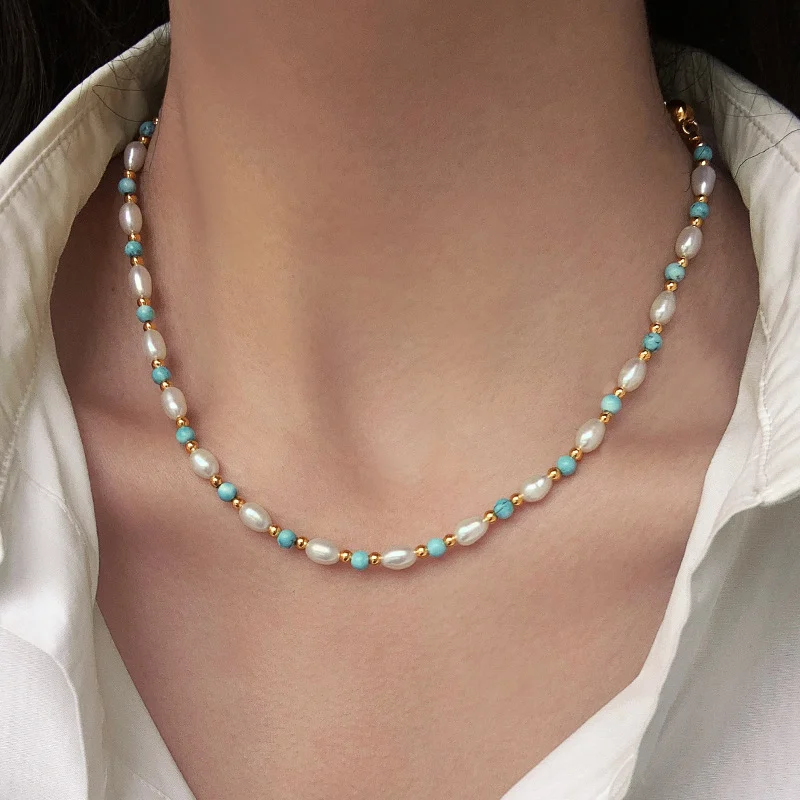 Woman wearing freshwater pearl turquoise collarbone necklace layered with thin gold snake chain