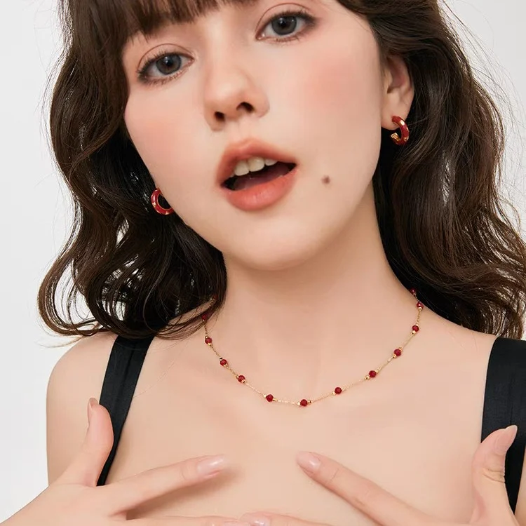 Young woman wearing french vintage red agate station choker and matching red hoop earrings, black camisole styling