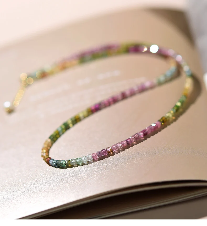 Flat lay lifestyle shot of rainbow tourmaline beaded choker on book page