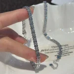 Hand‑held close‑up of S999 sterling silver shell geometric bracelet, showing delicate chain texture