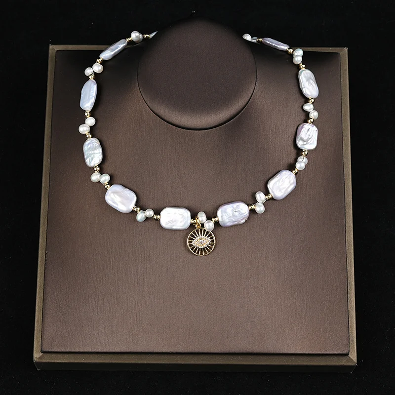 Model wearing baroque freshwater pearl choker necklace with sun-shaped zircon pendant, paired with black blazer and camisole