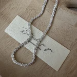 Close-up flat lay of S925 sterling silver crushed sparkle bead chain detail, shimmering silver fragments texture