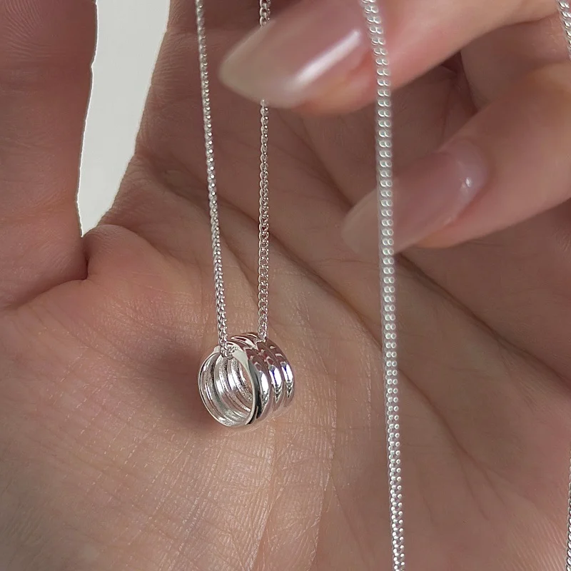 Macro close-up of S925 sterling silver multi stacked ring pendant held in palm, polished glossy circle detail