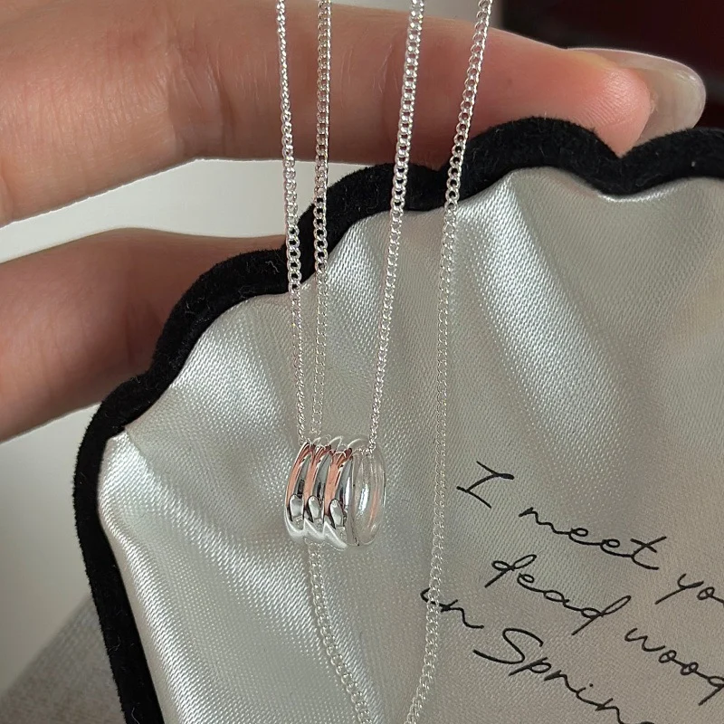 S925 sterling silver multi ring pendant necklace laid on black scalloped jewelry pouch, flat lay product shot