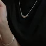 S925 matte crescent silver necklace worn with matching silver bangle bracelet on black top