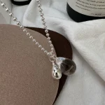 Close-up of natural clear teardrop crystal and polished silver teardrop pendant for S925 bead chain necklace