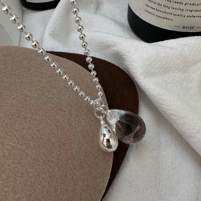 Close-up of natural clear teardrop crystal and polished silver teardrop pendant for S925 bead chain necklace