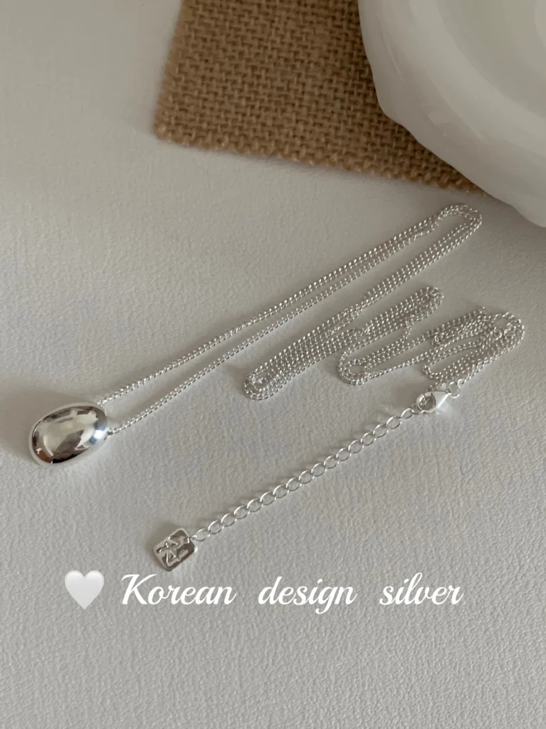 Full S925 sterling silver bean pendant necklace laid flat, showing curb chain, extension chain and square tag