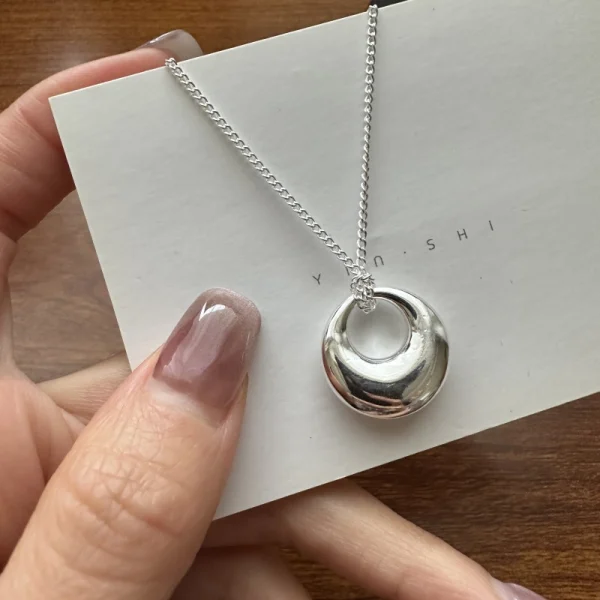 S925 sterling silver hollow donut ring pendant necklace held on white card, main product shot