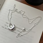 Full S925 hollow donut silver necklace laid flat on book, showing lobster clasp and complete chain