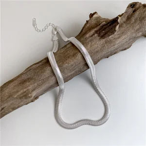 S925 sterling silver flat snake chain choker necklace laid on dry wood branch, minimalist silver jewelry display